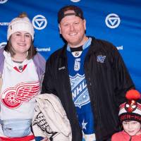 Two adults and one kid posing for photo in front of blue GVSU backdrop